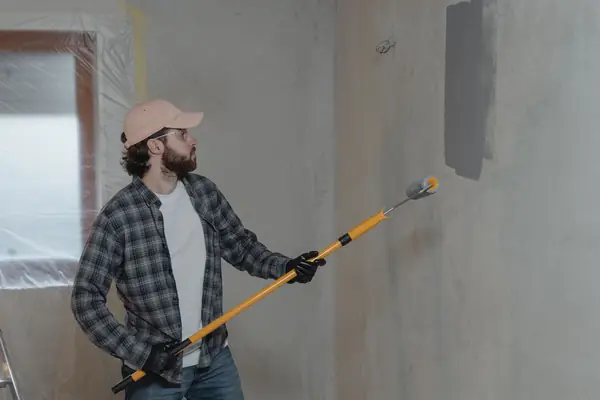 Painter rolling grey paint onto an interior wall in Green Bay